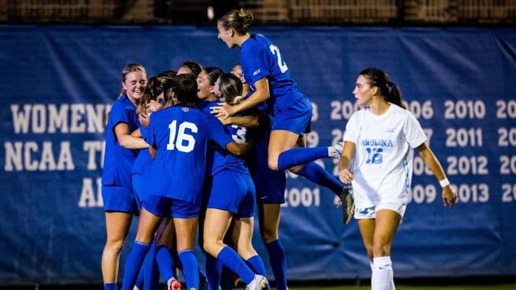 Joueuses en maillots bleus célébrant ensemble sur un terrain de football